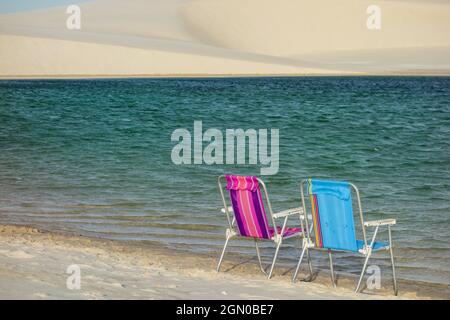 Sedie da spiaggia su una costa di una laguna limpida nel parco nazionale di Lencois Maranhenses in Brasile Foto Stock