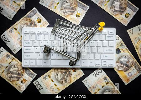 Tastiera per computer bianca su sfondo nero, Mini carrello, banconote polacche di duecento zlotys, concetto di e-commerce business market e s. Foto Stock