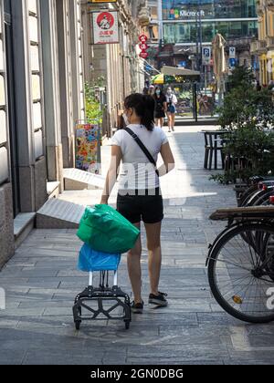 MILANO, ITALIA - 08 ago 2021: Un colpo verticale di una donna cinese con un carrello pieghevole all'aperto a Chinatown, Milano, Italia, estate 2021 Foto Stock