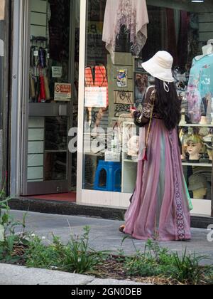 MILANO, ITALIA - 08 ago 2021: Un primo piano di una donna che cammina su un marciapiede con un lungo abito viola, Milano, Italia Foto Stock