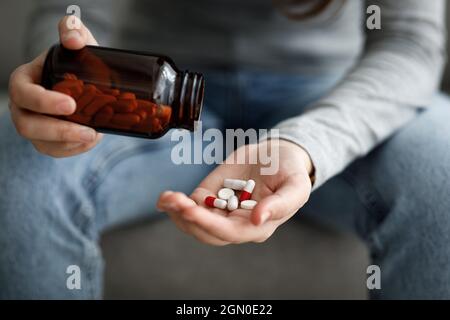 Cropped la giovane signora europea turbata da depressione, dolore e solitudine mette un sacco di pillole in mano a casa, primo piano. Suicidio, p. Mentale Foto Stock