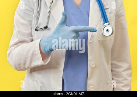 Il dito medico mostra la direzione per tornare a casa. Medico in guanti protettivi e uniforme medica, primo piano Foto Stock