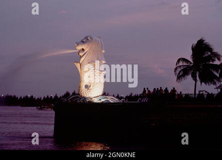 Singapore. Statua di Merlion all'ingresso del porto, illuminata di notte. Foto Stock