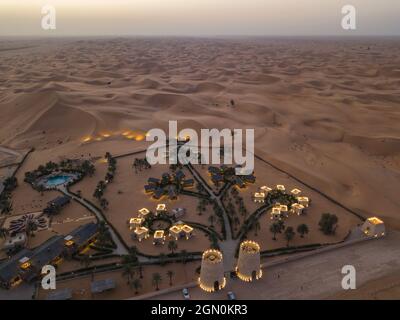 Vista aerea del resort deserto Arabian Nights Village tra dune al tramonto, Arabian Nights Village, Razeen Area di al Khatim, Abu Dhabi, United Arab EMI Foto Stock