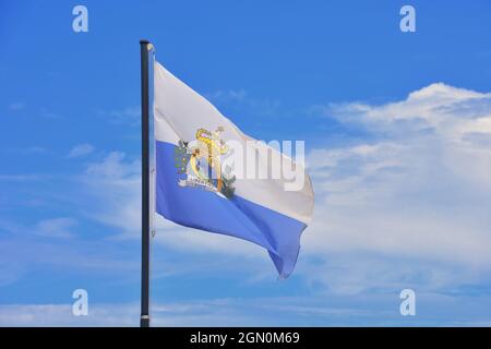 Repubblica di San Marino. La bandiera nazionale sammarinese sventola nel vento contro un cielo blu durante le celebrazioni della Fondazione della Repubblica. Foto Stock