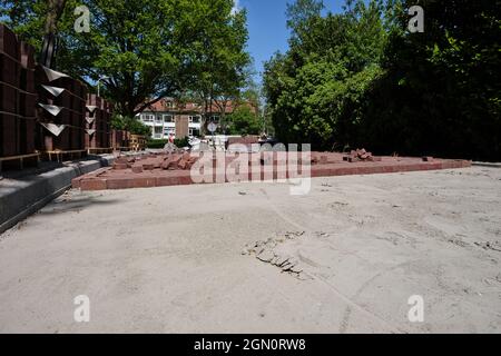 Costruzione di una strada acciottolata. Mucchio di ciottoli con sabbia e segnaletica, blocco residenziale, zona residenziale, case sullo sfondo. Foto Stock