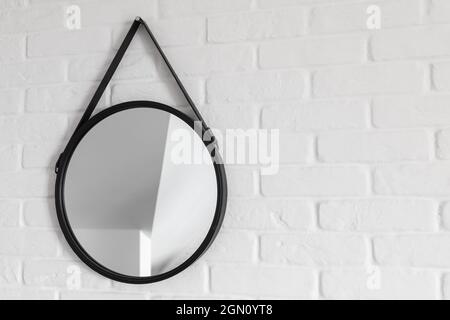 Astratto sfondo moderno di interior design, specchio rotondo con riflessi sfocati appende sulla parete di mattoni bianchi Foto Stock