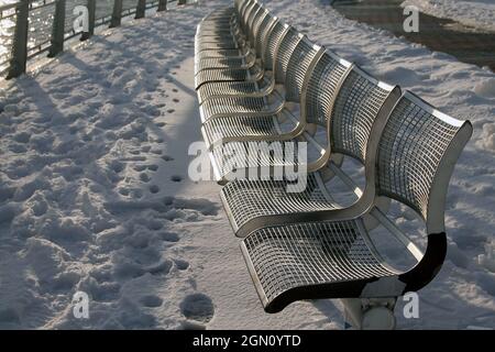 Le panchine metalliche e la neve bianca durante l'inverno a New York City Foto Stock