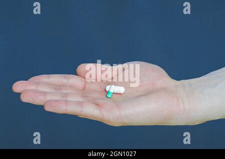 Due pillole rosso e giallo sul palmo in medicina mano. Foto Stock