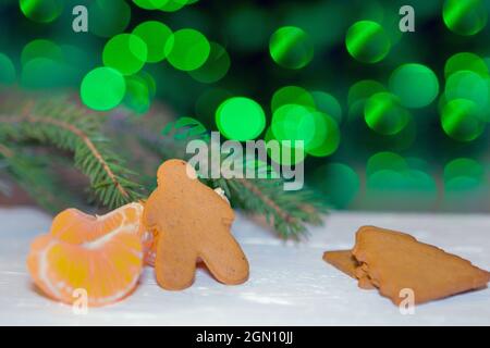 Biscotti fatti in casa di pan di zenzero biscotti di natale con mandarini vicino all'albero di abete su sfondo bianco Foto Stock