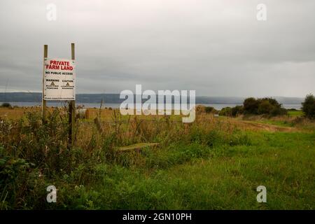 Terreno agricolo sulla penisola di Wirral con un segnale di avvertimento che indica che il terreno è privato e non consente l'accesso pubblico Foto Stock