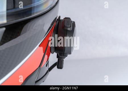 Un citofono su un casco rosso per motociclette isolato su bianco. Foto Stock