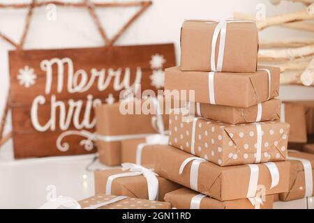 Decorazioni dello studio di Natale. Molti regali sotto forma di albero di Natale, un disegno di carta artigianale legato con una corda bianca e un arco. Asse di legno con Th Foto Stock