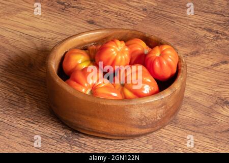 raccolta di pomodori appena raccolti in una ciotola di legno impilata sul pavimento Foto Stock