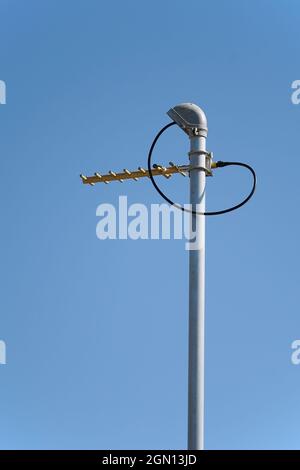 Antenna radio UHF su un palo rispetto al formato blu cielo verticale Foto Stock