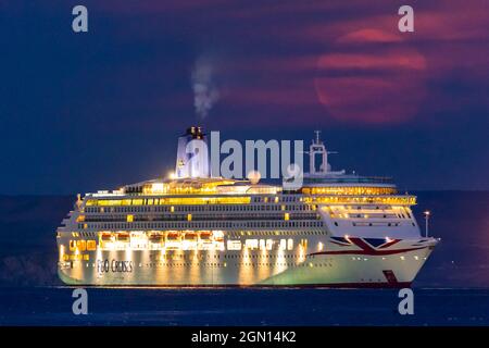 Weymouth, Dorset, Regno Unito. 21 settembre 2021. Meteo Regno Unito. La Luna piena di Harvest è oscurata da sottili alte nuvole come si alza da dietro la nave da crociera P&o Aurora che è ancorata nella baia a Weymouth in Dorset il l'ultimo giorno di estate astronomica. Picture Credit: Graham Hunt/Alamy Live News. Foto Stock