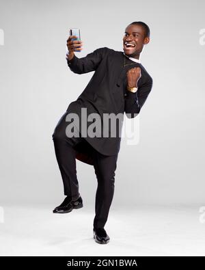 l'uomo africano che ha vinto qualcosa guardando il suo telefono gioire Foto Stock