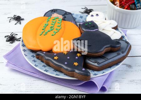 Halloween pani di zenzero, zucca, lapide, cappello di strega, gatto nero su un piatto su tavola di legno. Foto Stock
