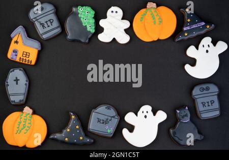 Halloween pani di zenzero, zucca, gatto, fantasma, lapide su sfondo nero con spazio copia. Foto Stock