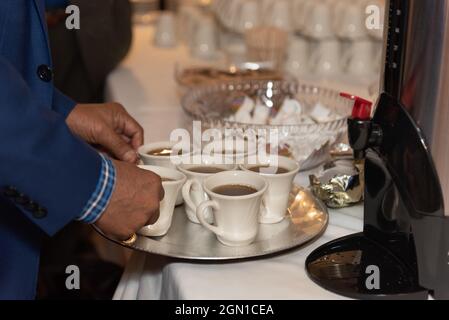 Caffè preparato impilato su un vassoio per riportare la famiglia a bere alla cena a banchetto. Foto Stock