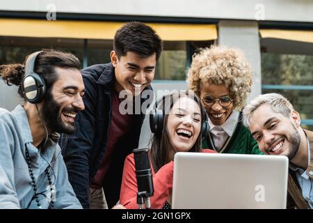 La gente felice che fa il podcast in linea usando il microfono ed il calcolatore del laptop - fuoco principale sul fronte asiatico dell'uomo Foto Stock