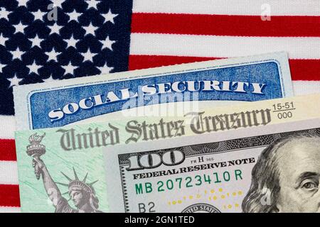 Tessera di previdenza sociale, assegno di tesoreria, 100 dollari di fattura e bandiera americana. Concetto di pagamento delle prestazioni di previdenza sociale, pensionamento e governanti federali Foto Stock