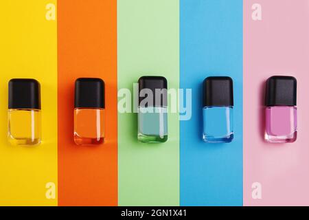 Vista dall'alto di bottiglie di smalto per unghie in diverse tonalità su una superficie colorata Foto Stock