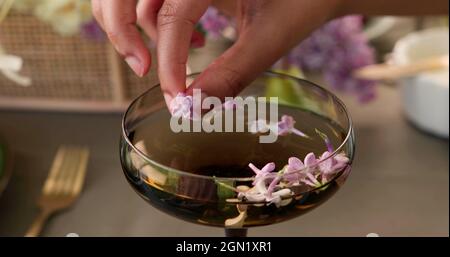 Mano di una donna che sta mettendo un fiore in un cocktail Foto Stock