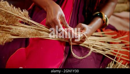 Mano di una donna africana che sta legando pianta asciutta Foto Stock