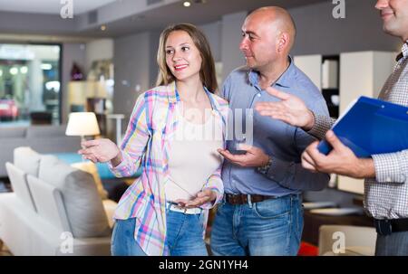 Maschio e femmina sono consultati con il venditore per scegliere un nuovo divano Foto Stock