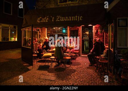 La gente si siede di fronte al Café &#39;t Zwaantje e gustare la birra di notte, West Terschelling, Terschelling, Isole Frisie Occidentali, Frisia, Paesi Bassi, UE Foto Stock