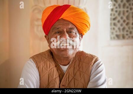 Uomo Rajasthani anziano con baffi tradizionali che portano un turbante zafferano in primo piano a Mehrangarh Fort, Jodhpur, Rajasthan, India Foto Stock