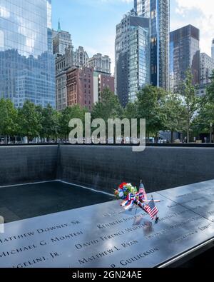 New York, USA, 21 settembre 2021 - bandiere e fiori statunitensi sono visti accanto ai nomi delle vittime dell'attacco terroristico alla memoria Nazionale del 11 settembre