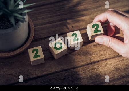 2022 felice anno nuovo con mano pick up blocco di legno su tavola di legno con luce solare da window.hope per nuovo anno concetto Foto Stock