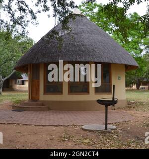 Capanna di alloggio tradizionale con tetto a paglia singolo con barbecue braai in Skukuza Rest Camp nel Parco Nazionale di Kruger in Sud Africa Foto Stock