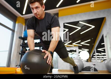 Fit giovane uomo che si esercita con la sfera di idoneità in una palestra Foto Stock