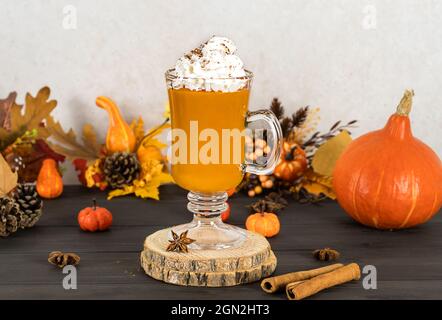 Spice latte di zucca, di stagione, dolce, calda bevanda autunnale. Frullato con panna montata. Sfondo in legno Foto Stock