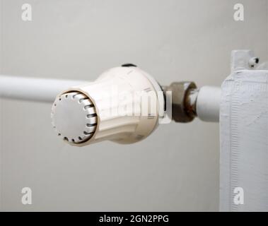 Prezzi del calore e concetto di crisi energetica. La manopola di regolazione della temperatura del radiatore di riscaldamento, il termostato, riduce i costi di riscaldamento. Foto Stock