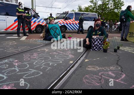 Gli attivisti delle ONG, partecipanti alla protesta sul cambiamento climatico, siedono sul terreno sotto la sorveglianza della polizia. Foto Stock