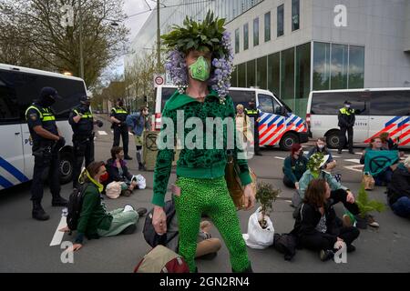 Un attivista di ONG partecipa alla protesta climatica indossando un costume con piante sulla testa. Foto Stock
