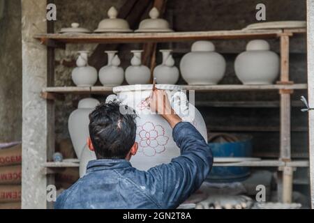 Cibuntu, Indonesia, 22/09/2021, Un artigiano disegna un fiore su un vaso di ceramica in Mekarbakti Village.vasi di ceramica da qui sono stati venduti a varie regioni in Indonesia come l'isola di Bali e sono stati venduti a paesi stranieri come gli Stati Uniti e l'Africa. I prodotti ceramici dall'Indonesia hanno varie forme che variano da caraffe di ceramica, decorazioni a forma di pesce, grandi vasi, statue di ceramica, piatti, bicchieri, a pagode. La gamma di prezzi dipende dalla dimensione e dal livello di complessità; il prezzo per un metro di vaso di ceramica alto è IDR 900,000 ($63.00). Foto Stock