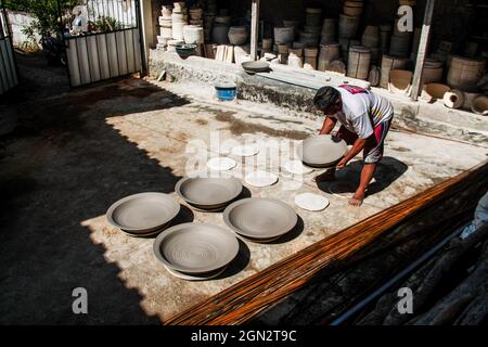 Cibuntu, Indonesia, 22/09/2021, Un artigiano è visto portare un piatto di ceramica per asciugare alla sua casa in Mekarbakti Village.vasi di ceramica da qui sono stati venduti a varie regioni in Indonesia come l'isola di Bali e sono stati venduti a paesi stranieri come gli Stati Uniti e l'Africa. I prodotti ceramici dall'Indonesia hanno varie forme che variano da caraffe di ceramica, decorazioni a forma di pesce, grandi vasi, statue di ceramica, piatti, bicchieri, a pagode. La gamma di prezzi dipende dalla dimensione e dal livello di complessità; il prezzo per un metro di vaso di ceramica alto è IDR 900,000 ($63.00). Foto Stock