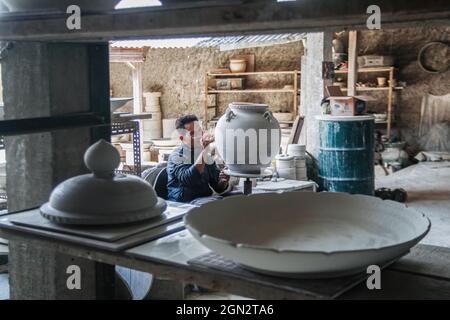 Cibuntu, Indonesia, 22/09/2021, Un artigiano disegna un fiore su un vaso di ceramica in Mekarbakti Village.vasi di ceramica da qui sono stati venduti a varie regioni in Indonesia come l'isola di Bali e sono stati venduti a paesi stranieri come gli Stati Uniti e l'Africa. I prodotti ceramici dall'Indonesia hanno varie forme che variano da caraffe di ceramica, decorazioni a forma di pesce, grandi vasi, statue di ceramica, piatti, bicchieri, a pagode. La gamma di prezzi dipende dalla dimensione e dal livello di complessità; il prezzo per un metro di vaso di ceramica alto è IDR 900,000 ($63.00). Foto Stock