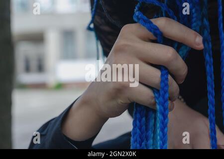 La mano di un uomo regola le trecce blu nei capelli della donna. Lungo b Foto Stock