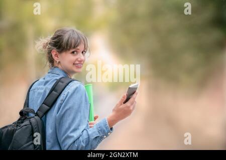 Donna bionda che guarda la macchina fotografica mentre tiene un telefono cellulare in mano Foto Stock