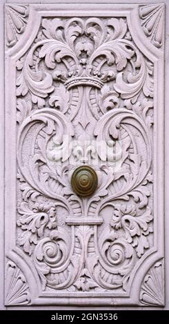 Primo piano di uno storico cancello cortile con maniglia porta e sculture in legno ornato in rosa crepuscolo Foto Stock