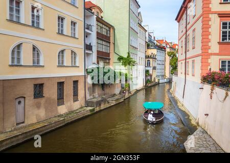 Certovka, barca da crociera con turisti che navigano tra gli edifici sul canale d'acqua nella città piccola, Praga, Repubblica Ceca Foto Stock
