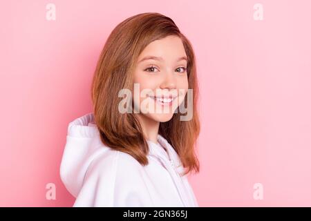 Foto di affascinante piccola scuola vestita felpa bianca sorridente spazio vuoto isolato colore rosa sfondo Foto Stock