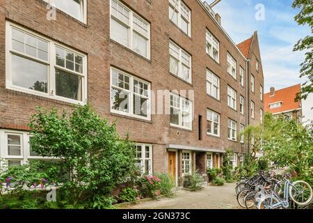 Biciclette parcheggiate nei pressi di alberi verdi e edifici in mattoni nel quartiere residenziale durante il giorno Foto Stock