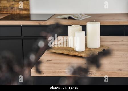 Candele bianche poste su un tavolo di legno contro un piano di lavoro Foto Stock